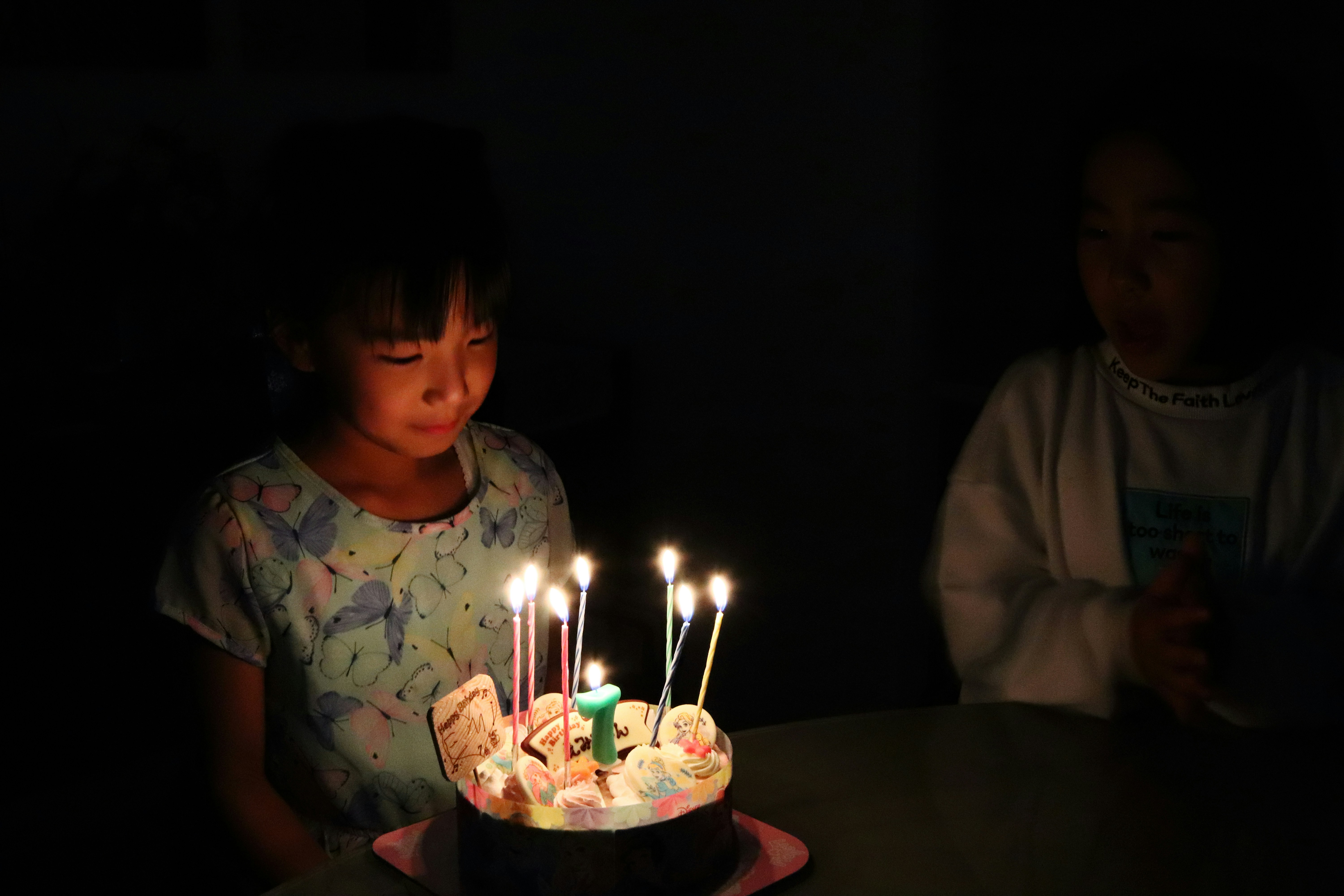 Petite fille devant un gâteau d'anniversaire avec bougies