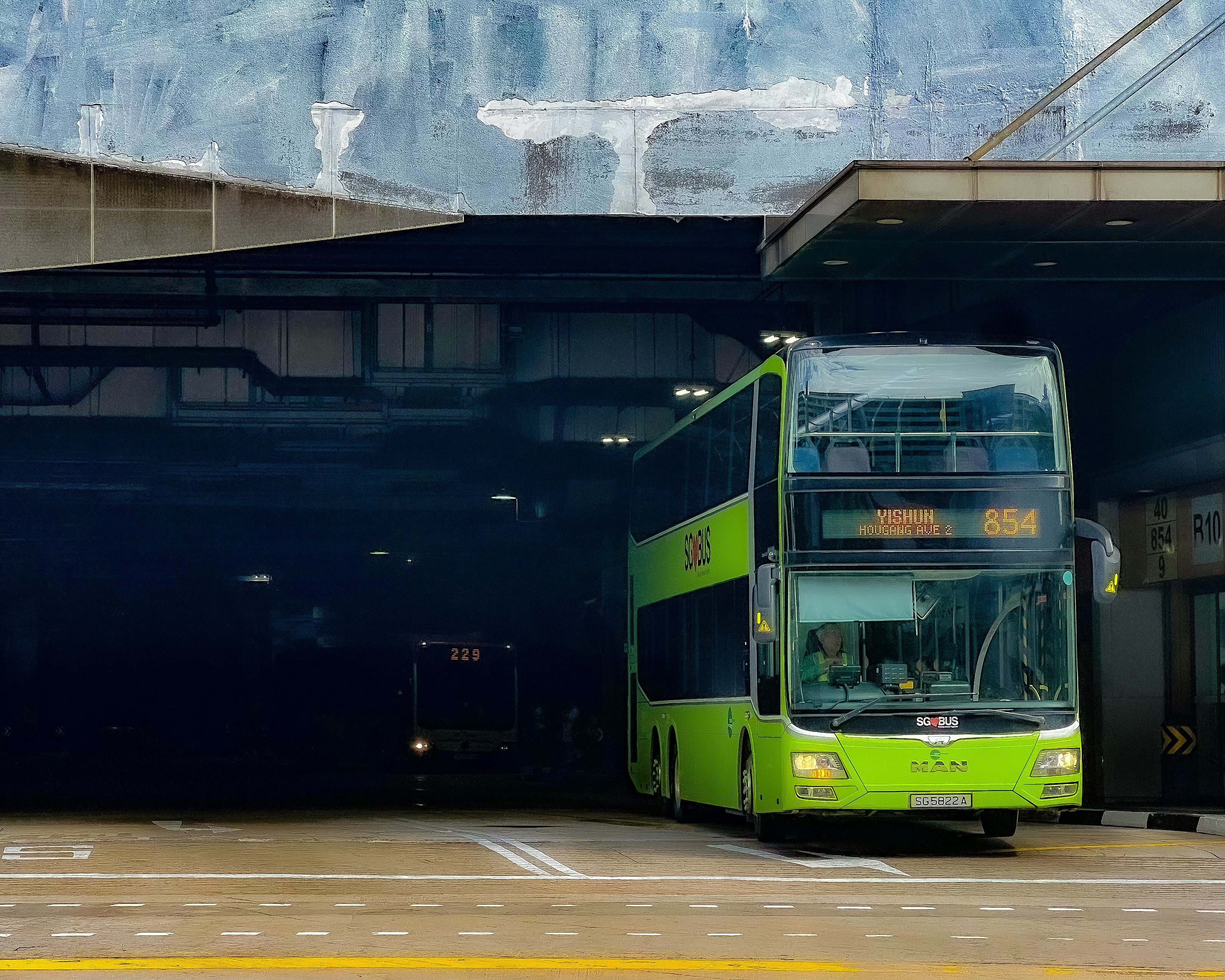 A green double decker bus parked in front of a building