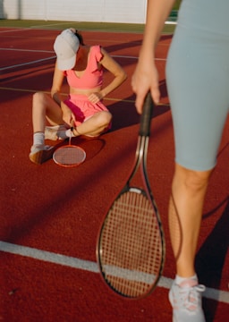 A woman kneeling down on a tennis court holding a racquet