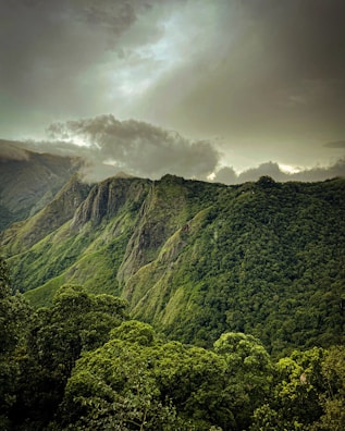 A view of a lush green mountain range under a cloudy sky