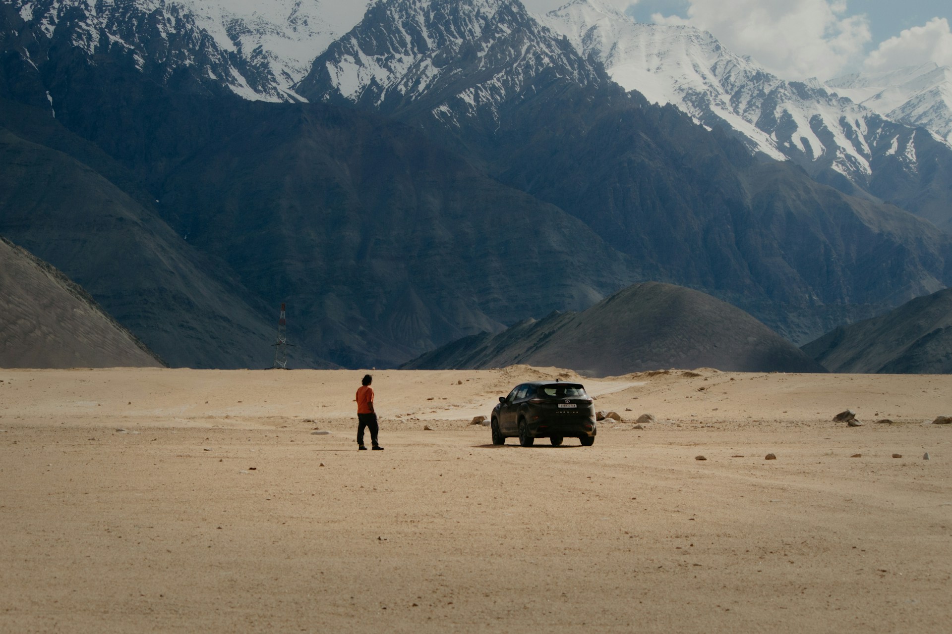 A person standing next to a car in the desert