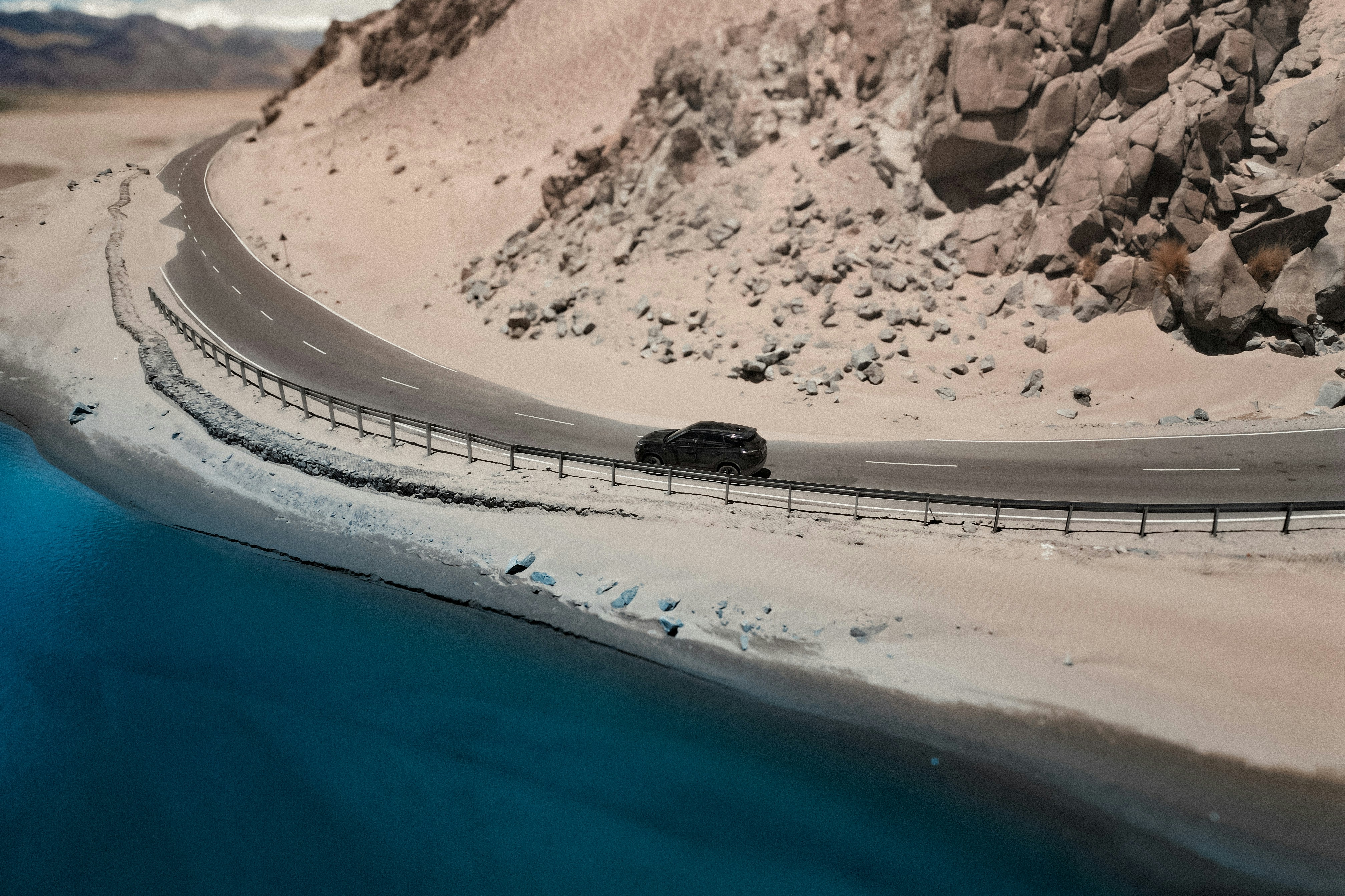 A car driving down a road next to a body of water