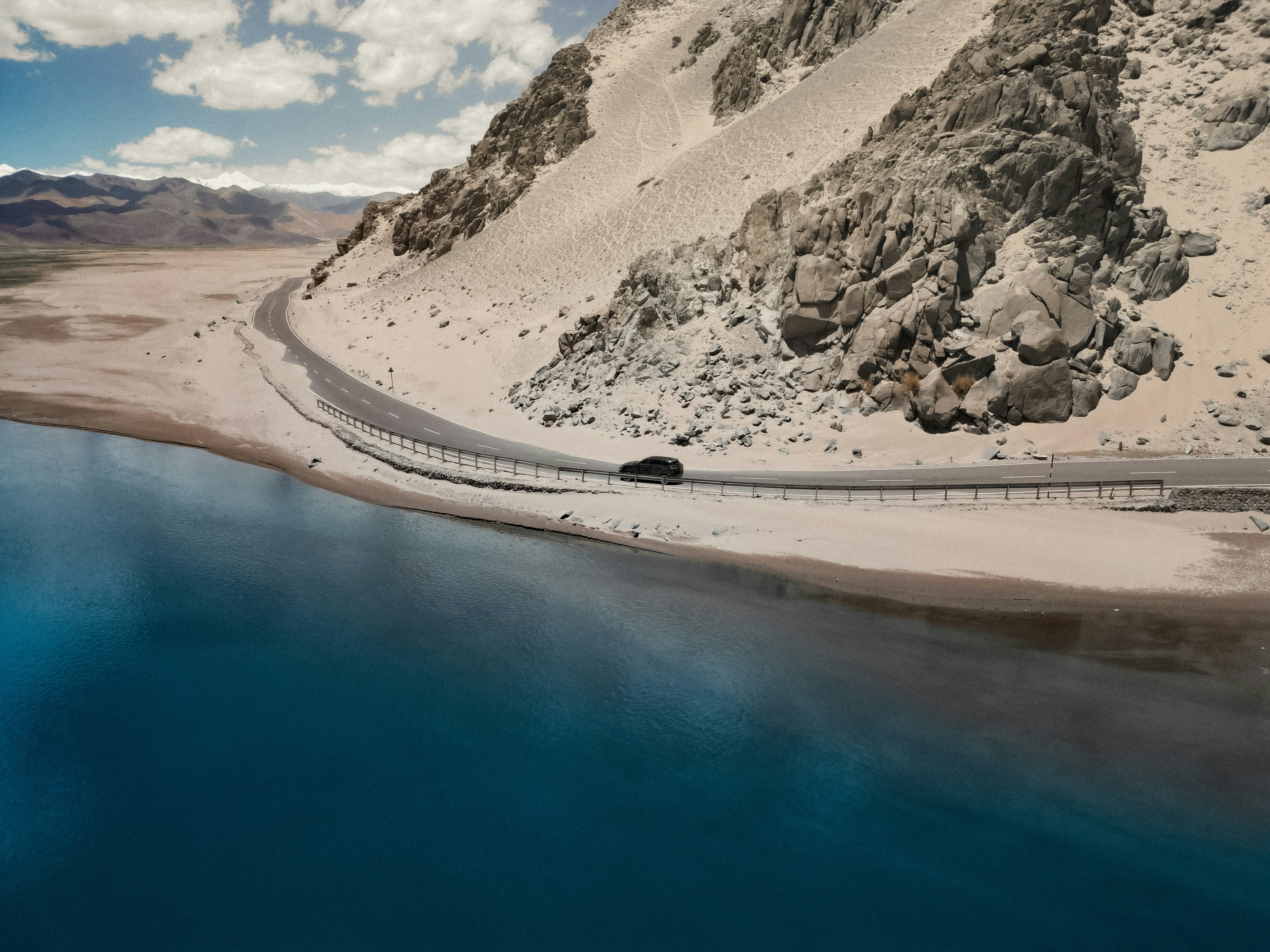 A car driving down a road next to a mountain