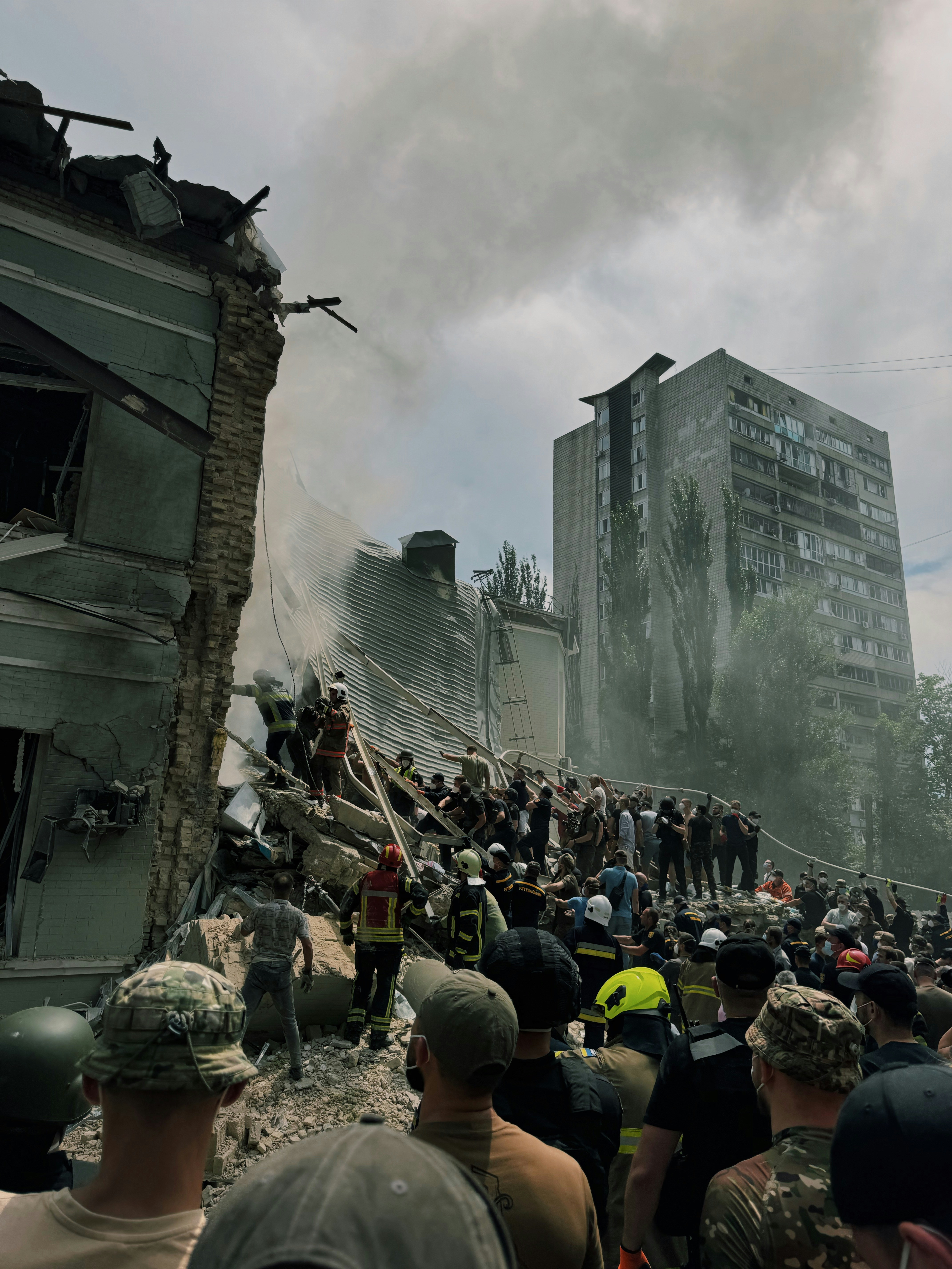 A large crowd of people standing around a destroyed building