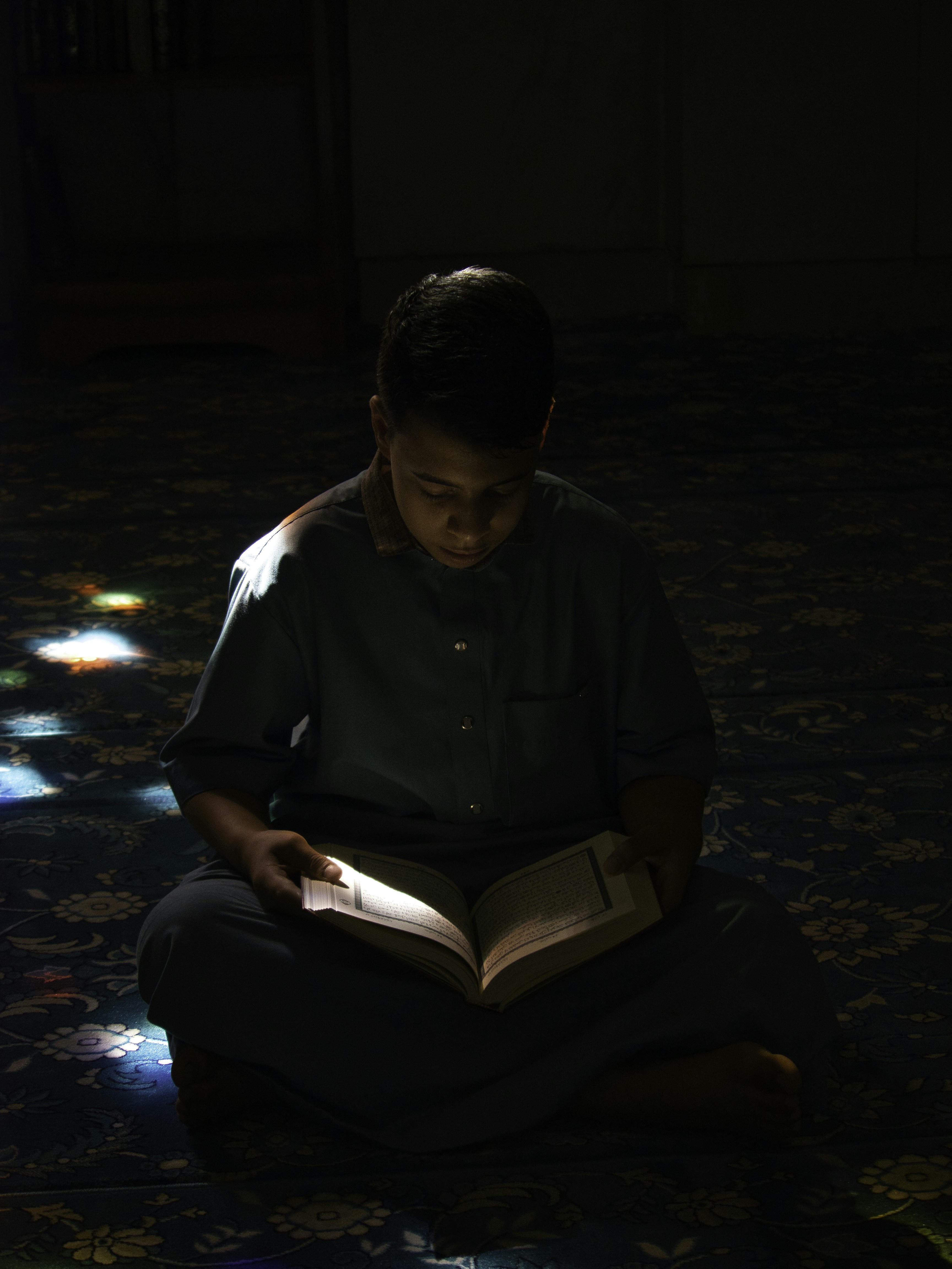 A boy sitting on the floor reading a book