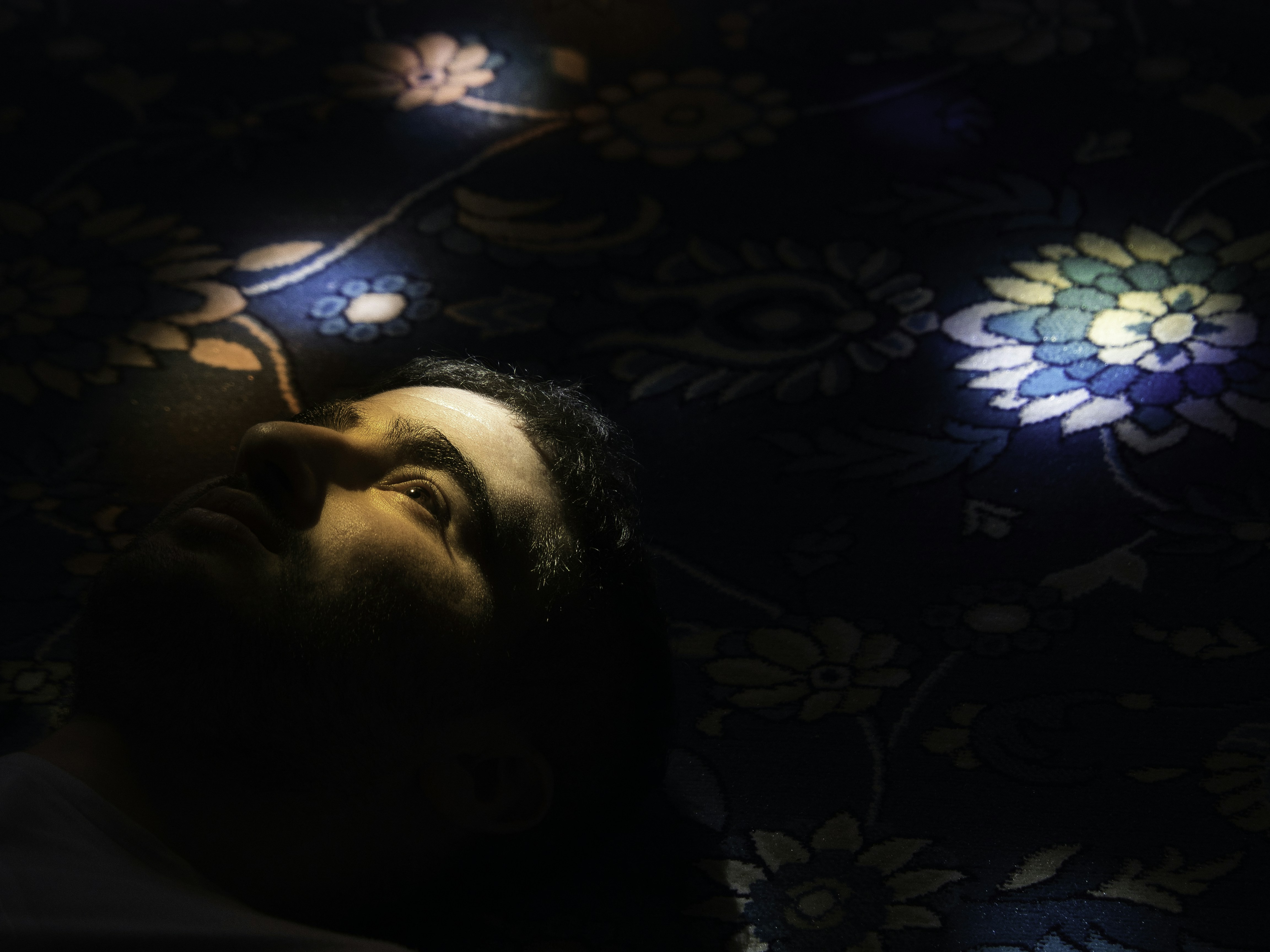 A man laying on a bed in the dark