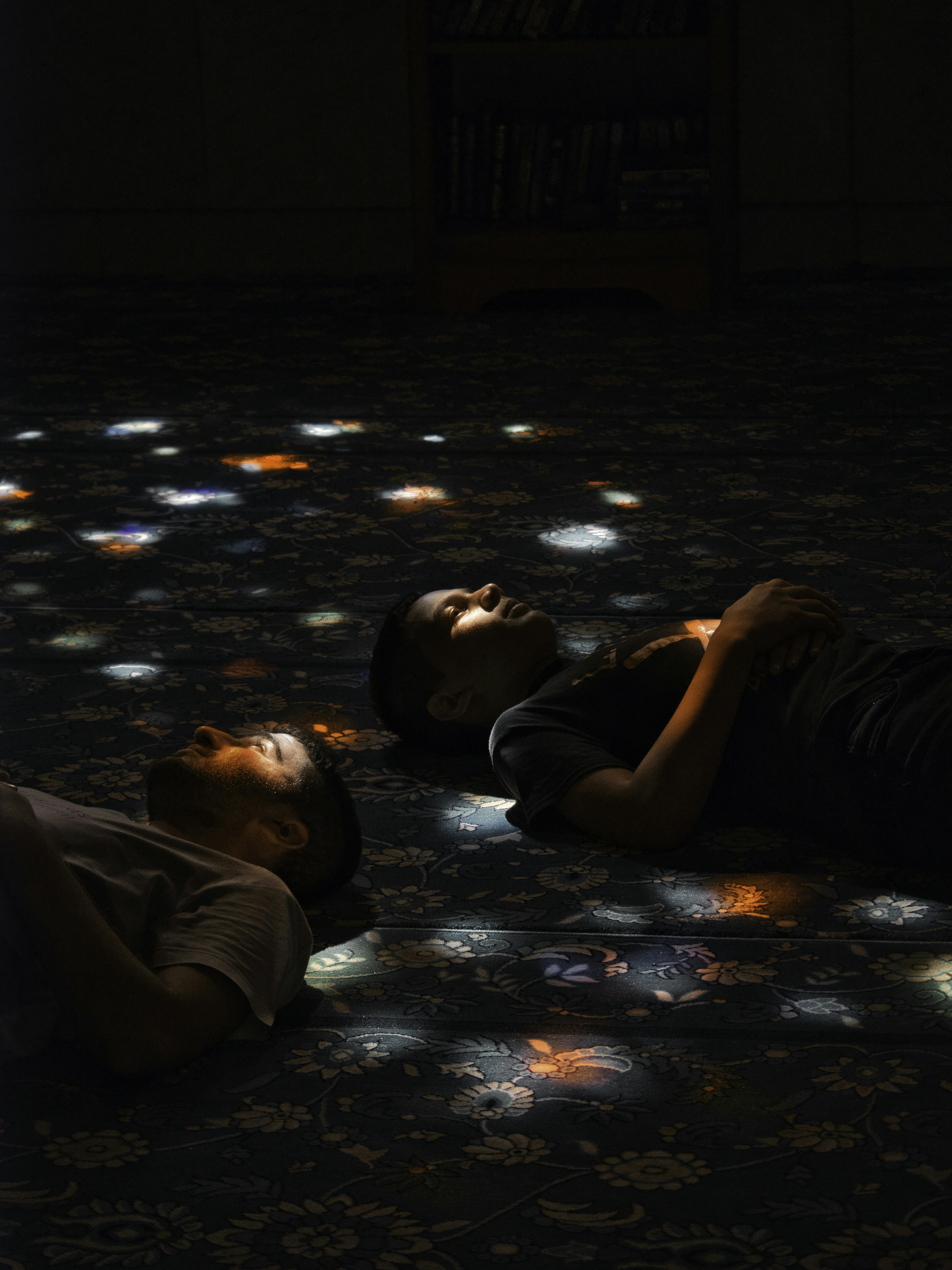 Two young men laying on the floor in the dark