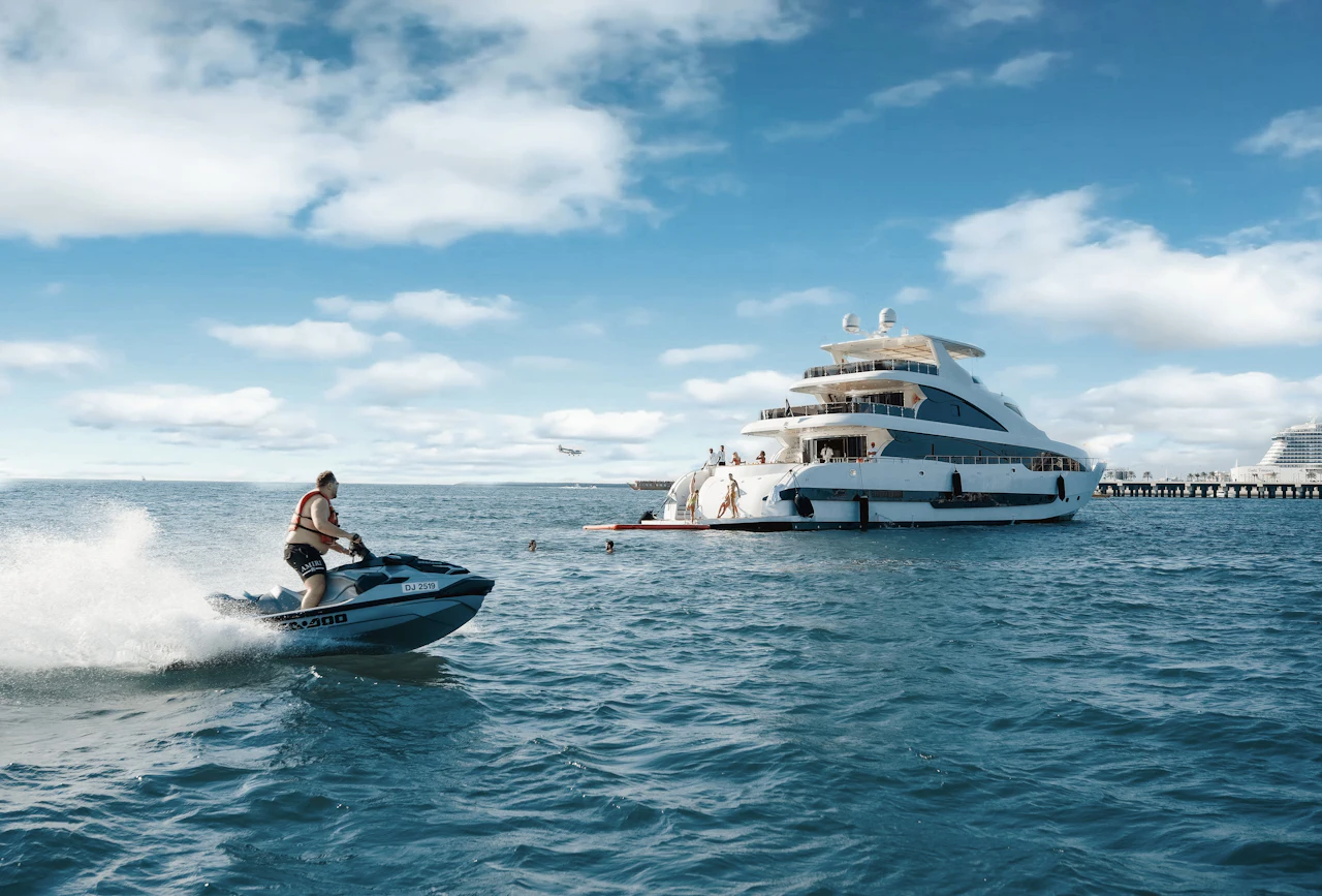 Jet ski riding beside a white yacht on a sunny day