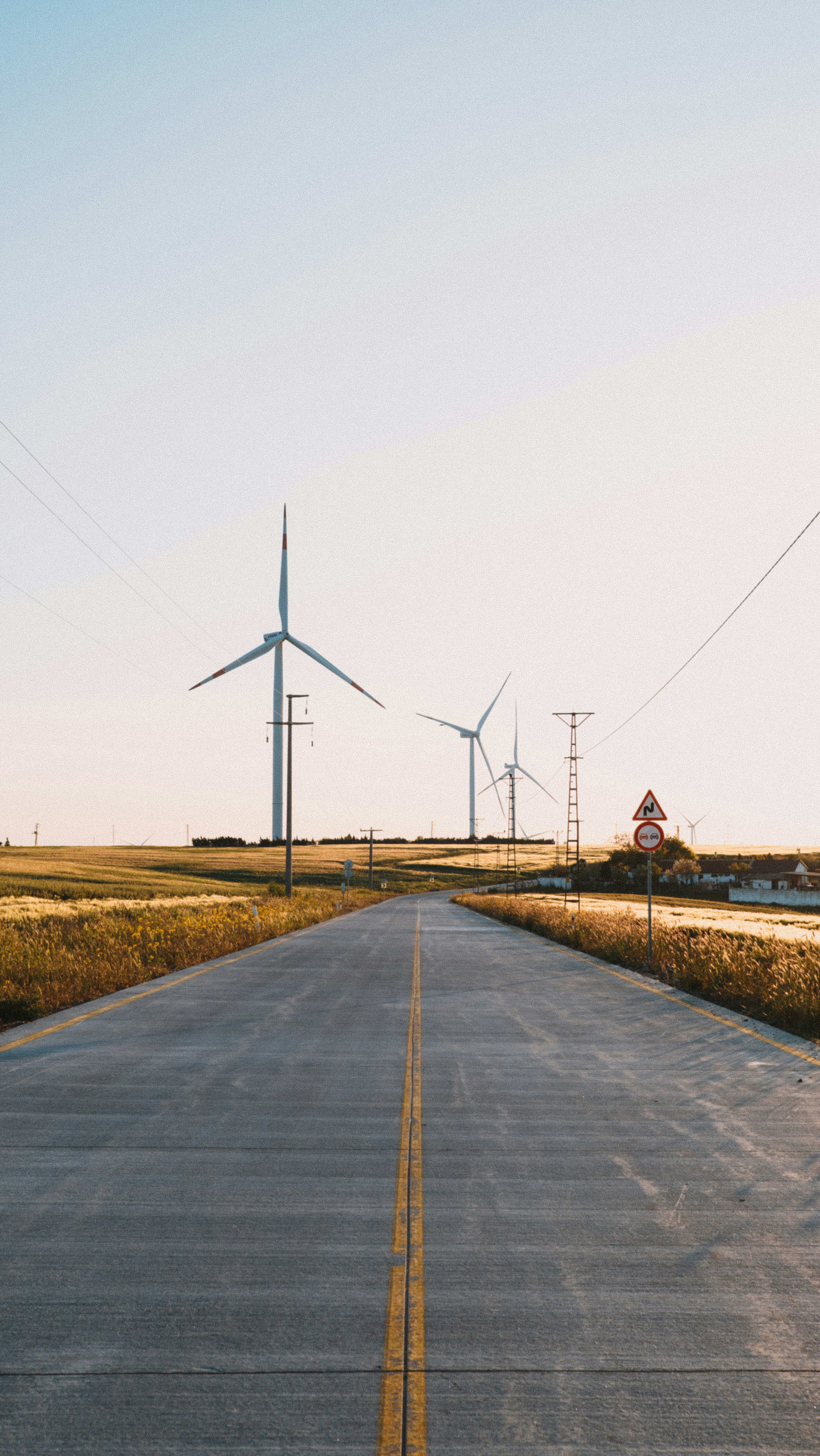 An empty road with wind turbines in the distance