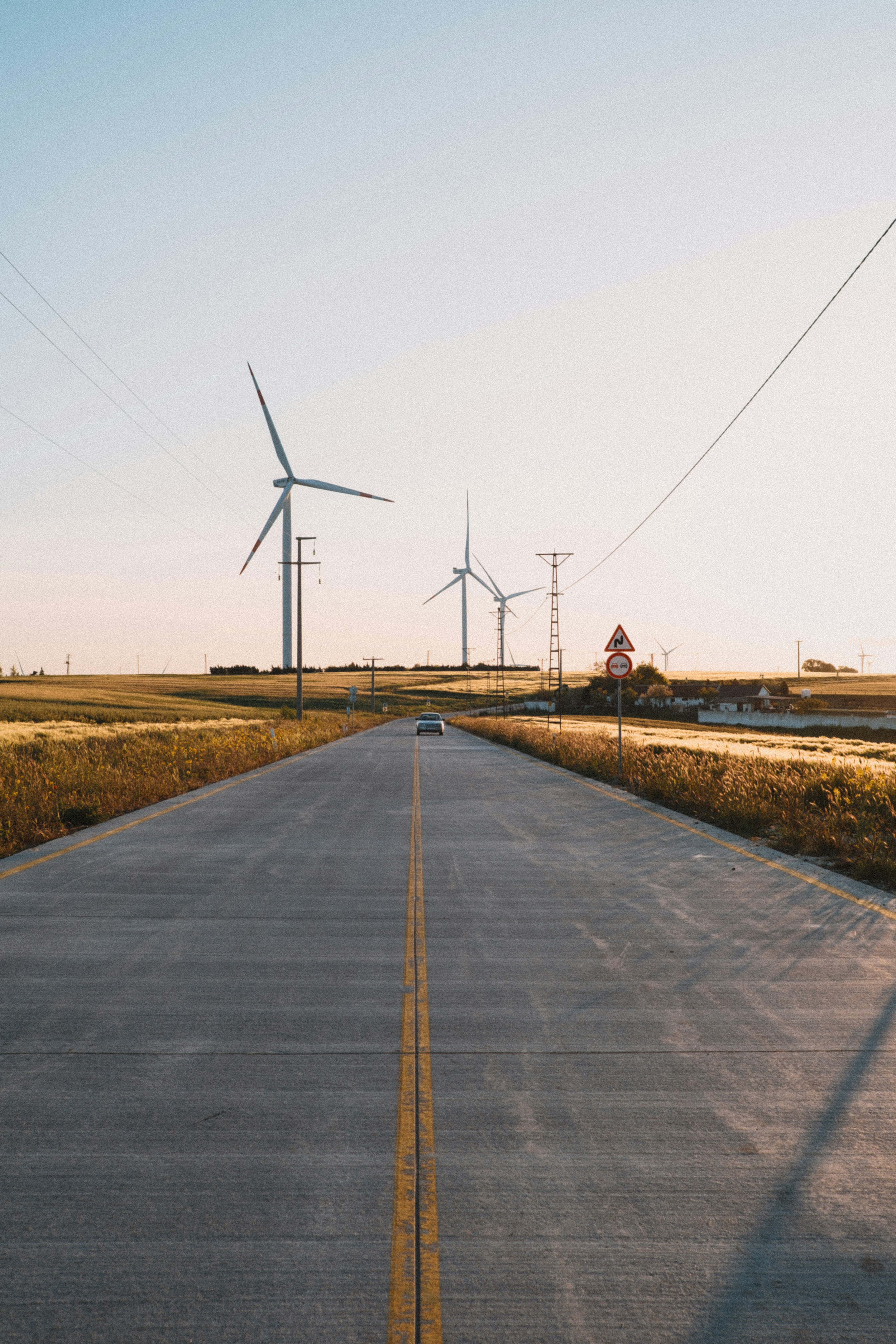 An empty road with wind turbines in the background
