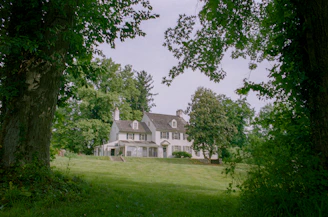A large white house surrounded by trees and grass