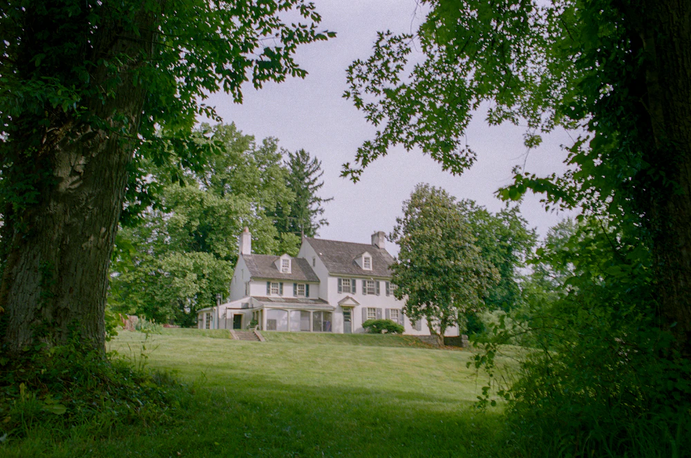 Elegant white farm house estate surrounded by trees and lawns