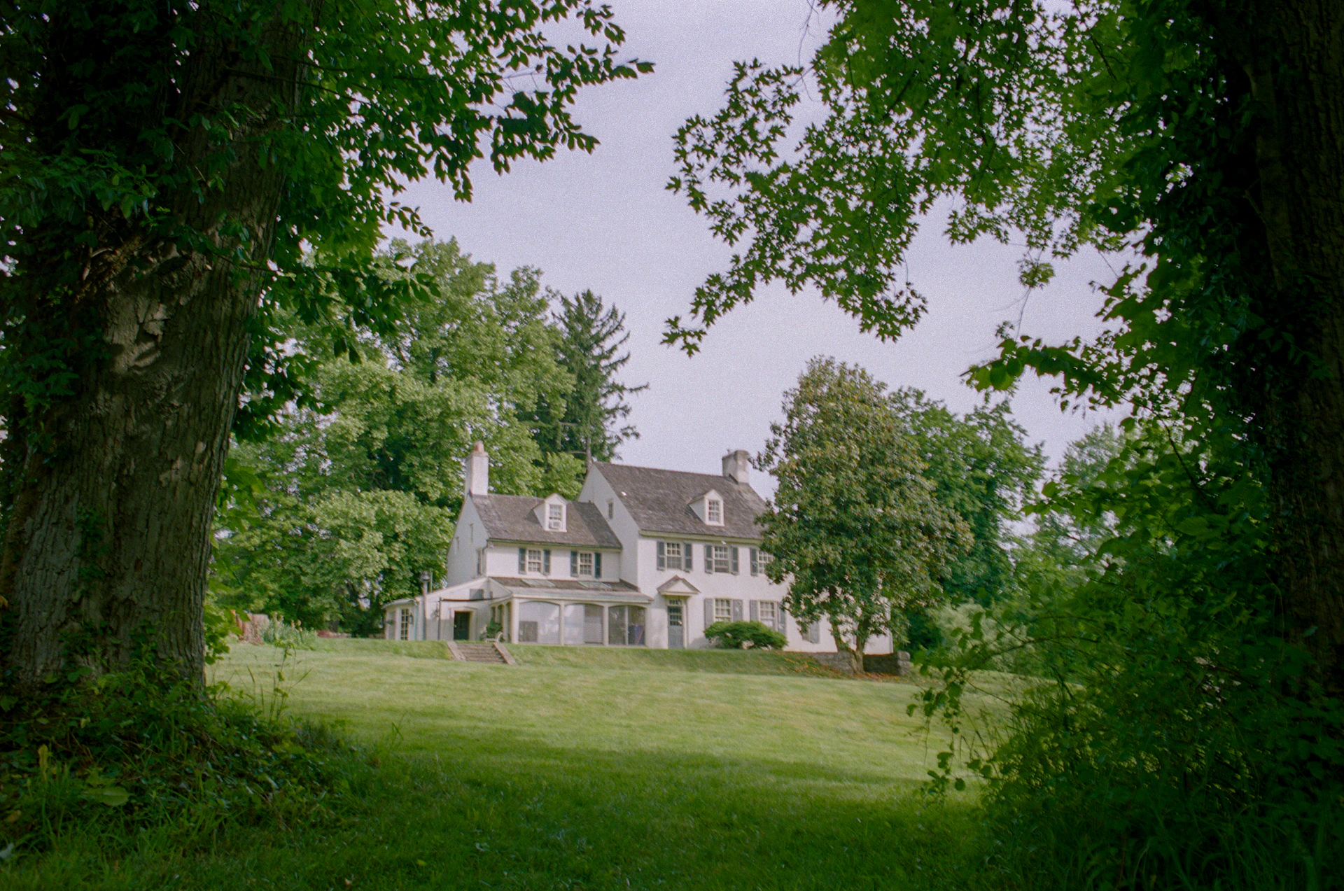 A large white house surrounded by trees and grass