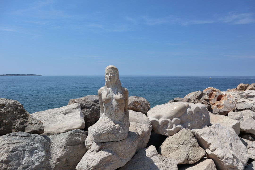 A statue sitting on top of a pile of rocks next to the ocean,