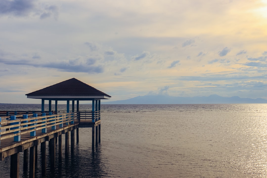 A pier with a gazebo in the middle of the water, Almost sunset by the beach