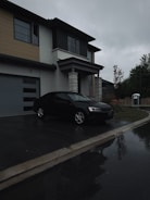 A black car parked in front of a house