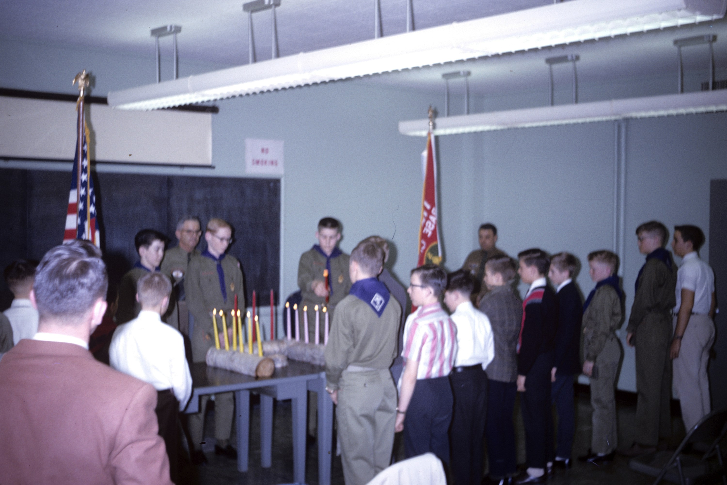 A group of people standing around a table with a cake