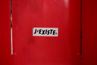 A red door with a white sticker on it