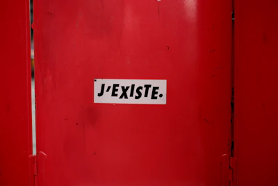 A red door with a white sticker on it