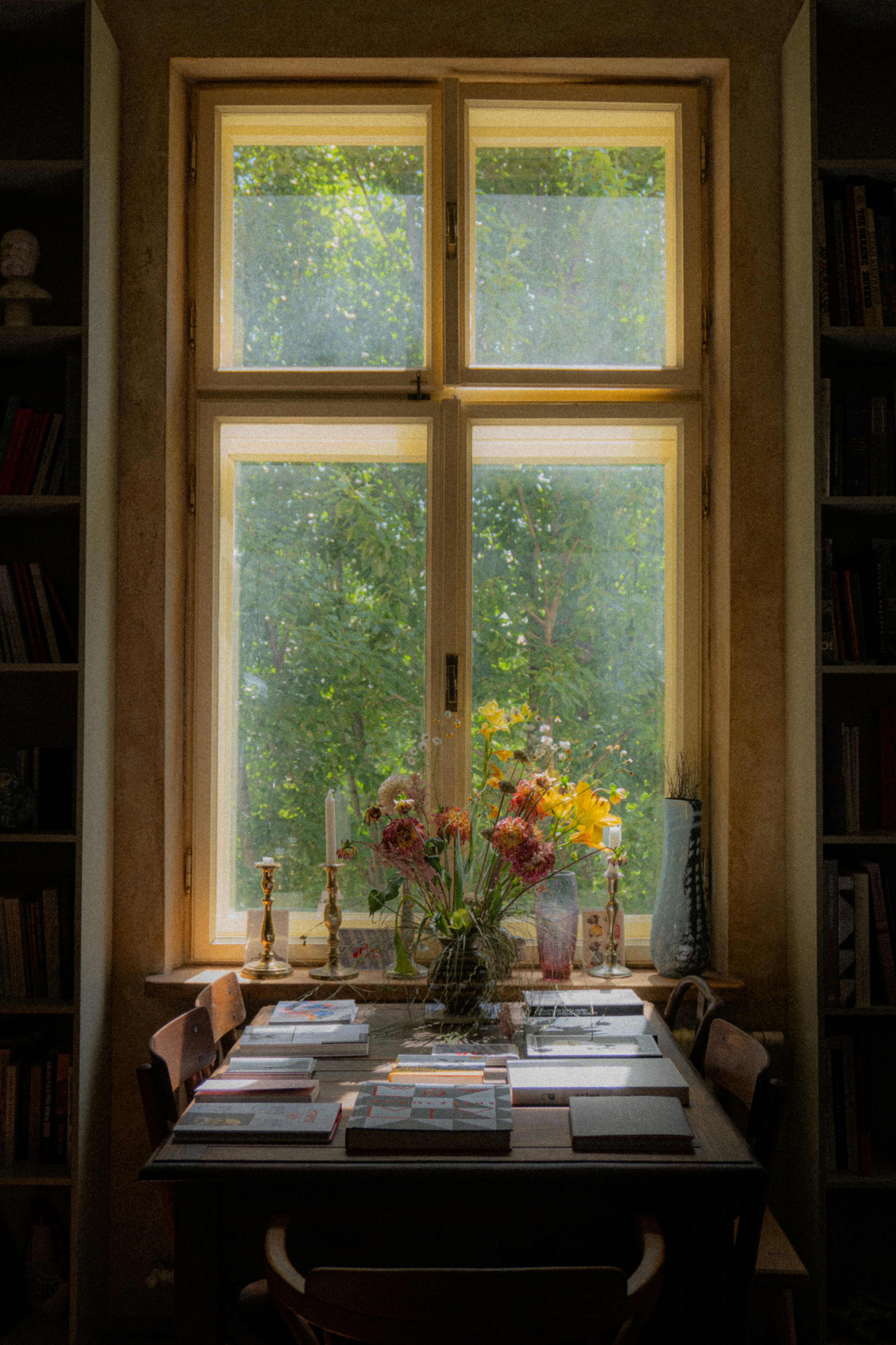 A table with a vase of flowers on it in front of a window