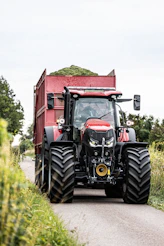 A red tractor driving down a country road