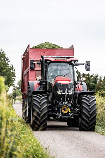 A red tractor driving down a country road