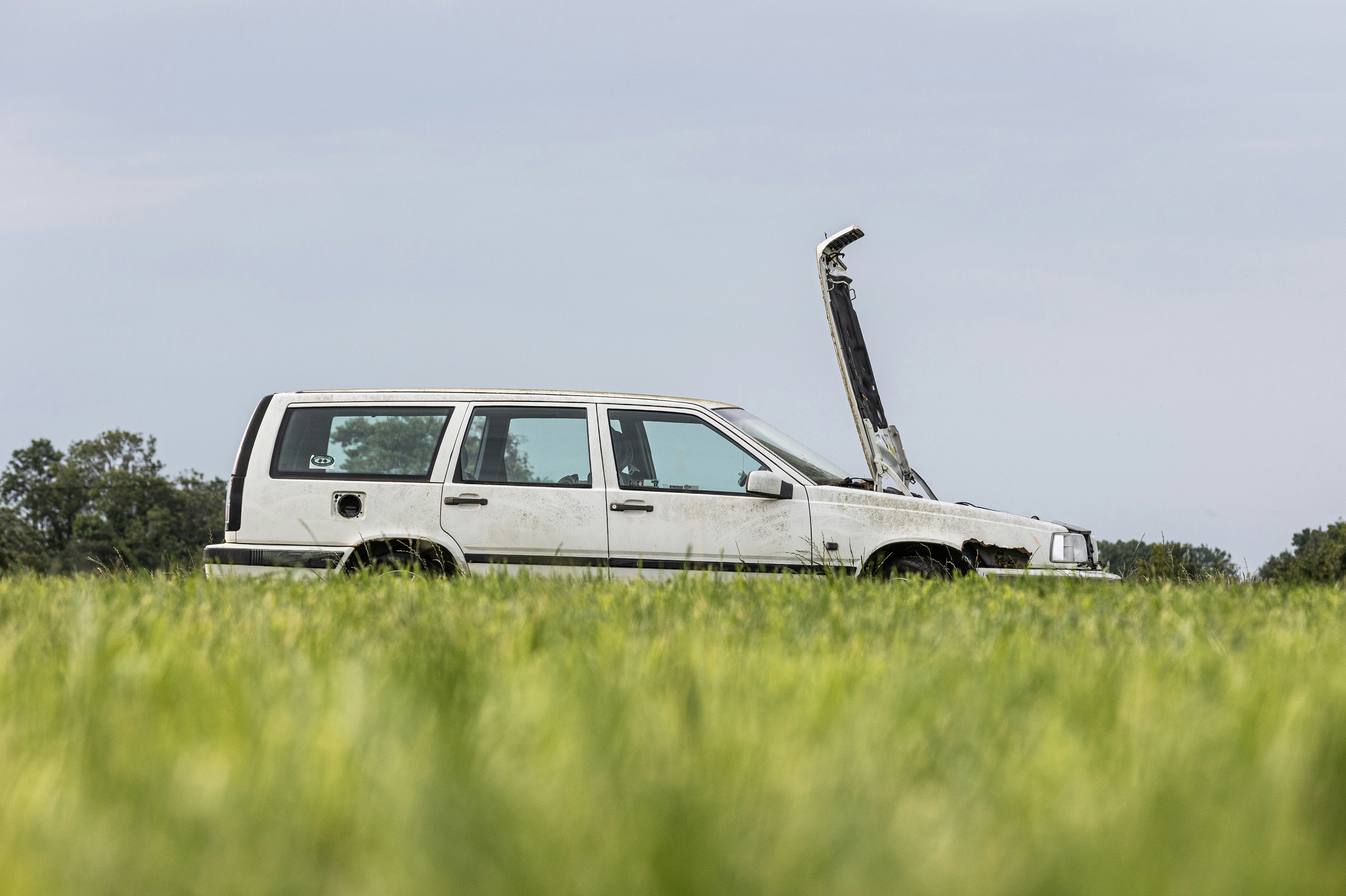 A white van parked in a field of green grass