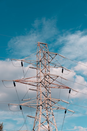 A high voltage transmission tower against a blue sky, part of the power grid that serves Henderson homes and large data centers