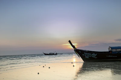 A boat sitting on top of a beach next to the ocean