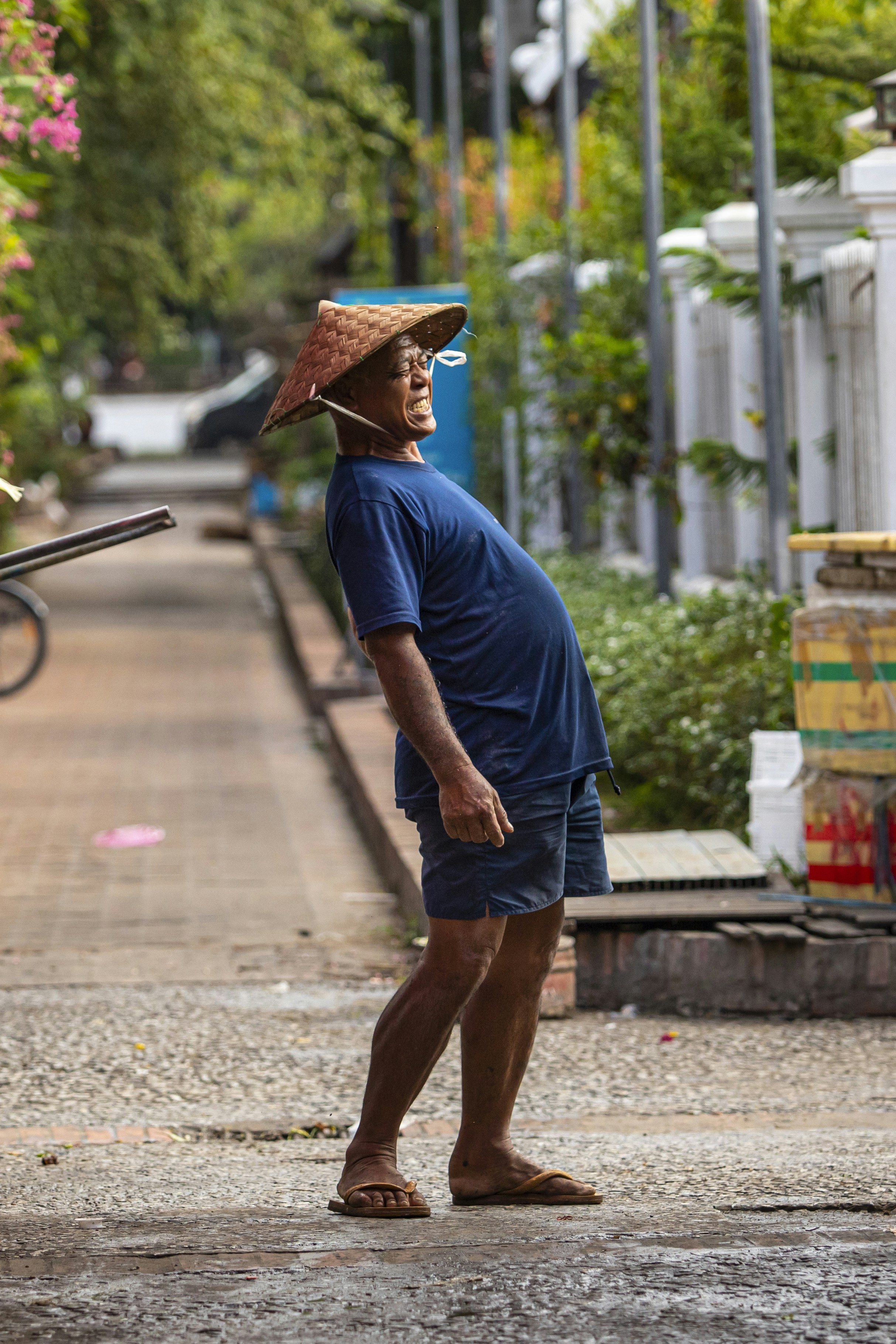 A man with a straw hat on his head walking down a street
