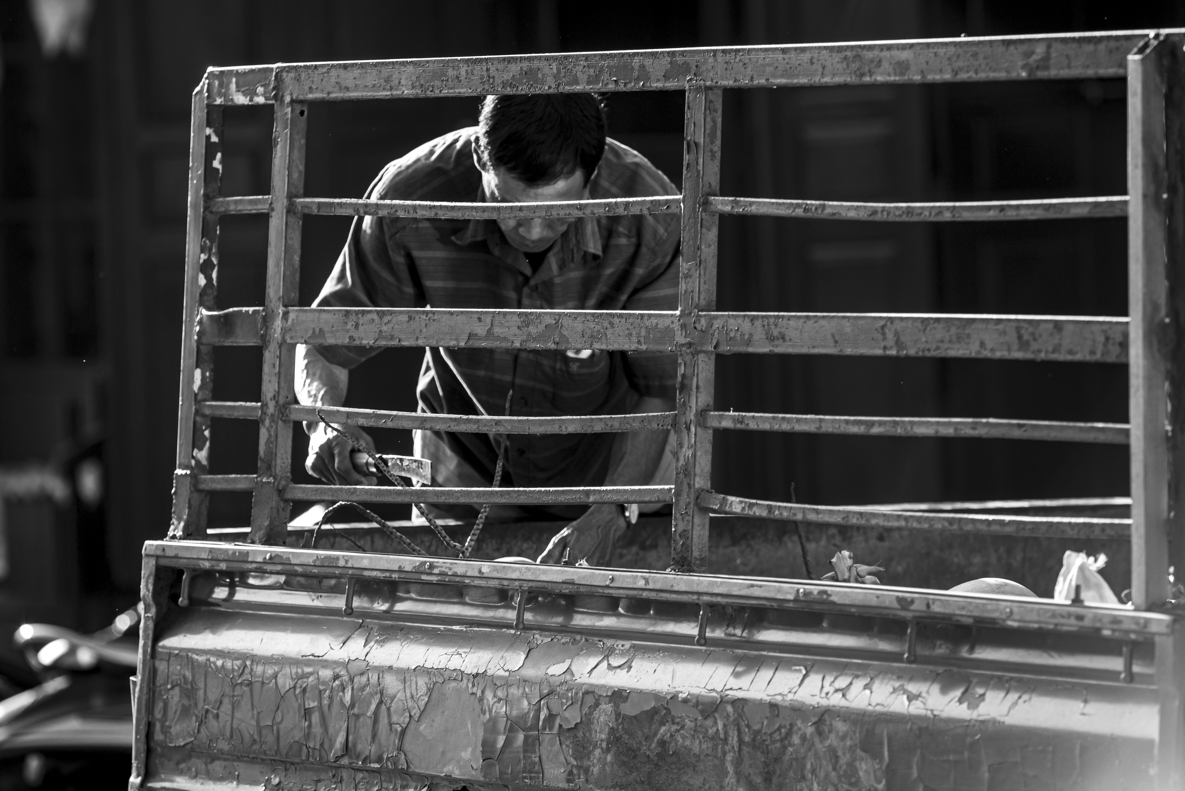 A black and white photo of a man working on a truck