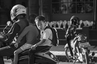 A black and white photo of two boys on a motorcycle