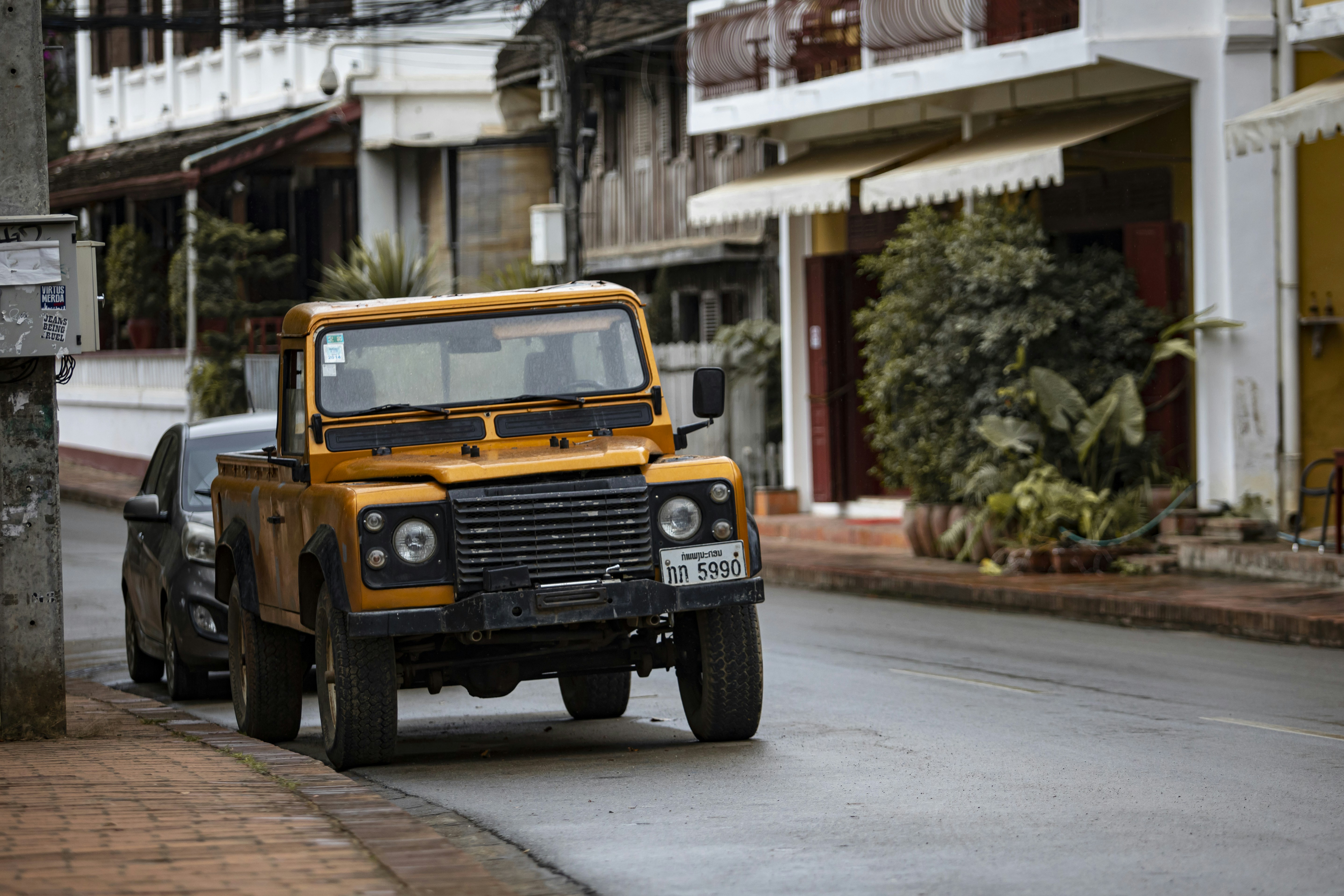 A yellow truck driving down a street next to tall buildings