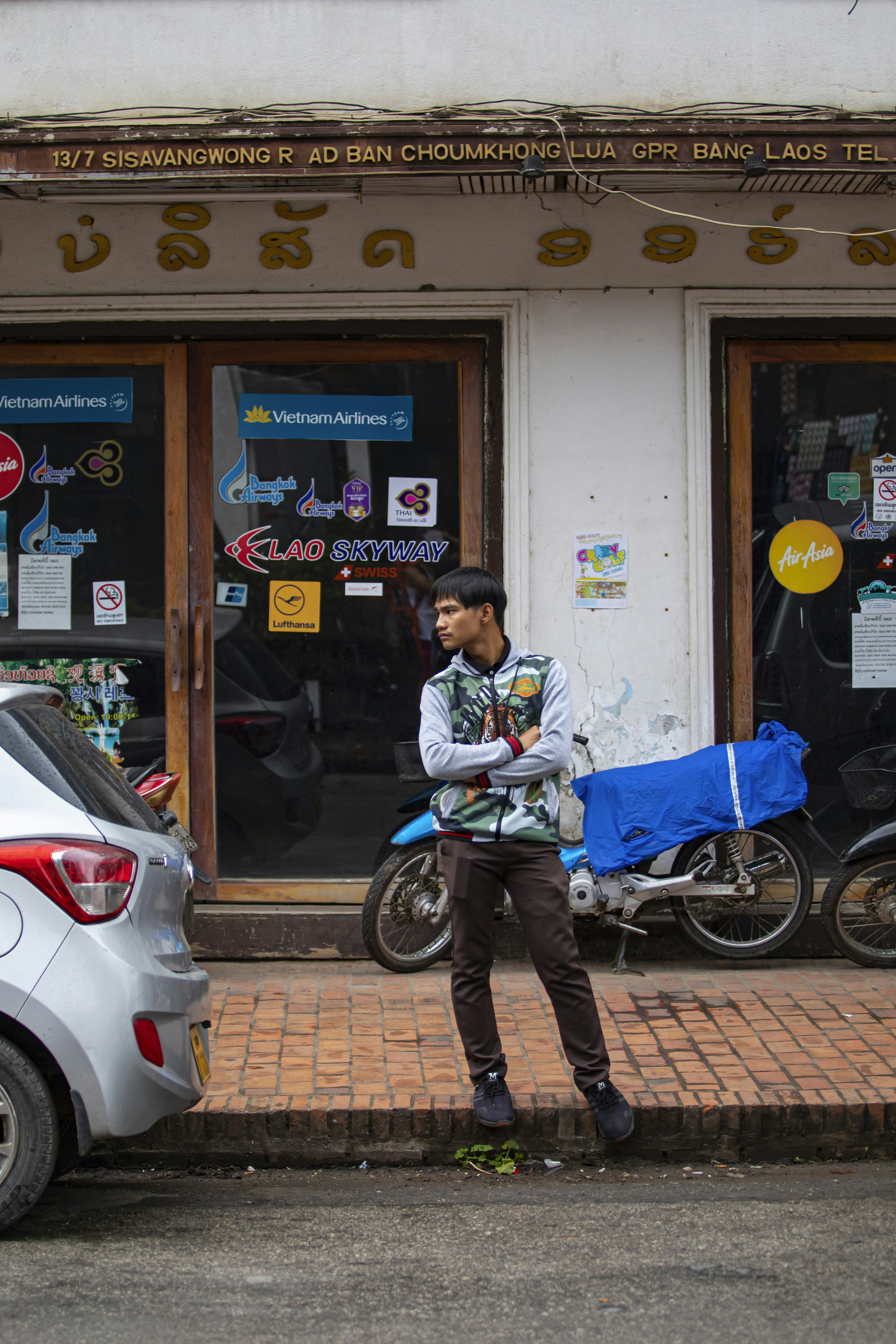 A man standing in front of a building next to a parked car