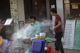 A group of people standing around a table with food on it