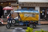 A small yellow and blue truck driving down a street