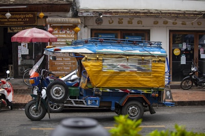 A small yellow and blue truck driving down a street