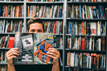 A man holding up a book in front of a library full of books