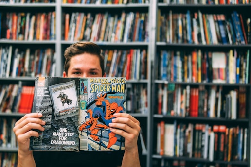 A man holding up a book in front of a library full of books