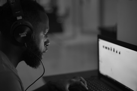 A man sitting in front of a laptop computer wearing headphones
