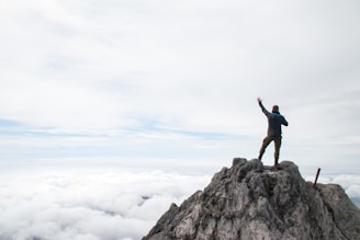 A man standing on top of a mountain with his arms in the air