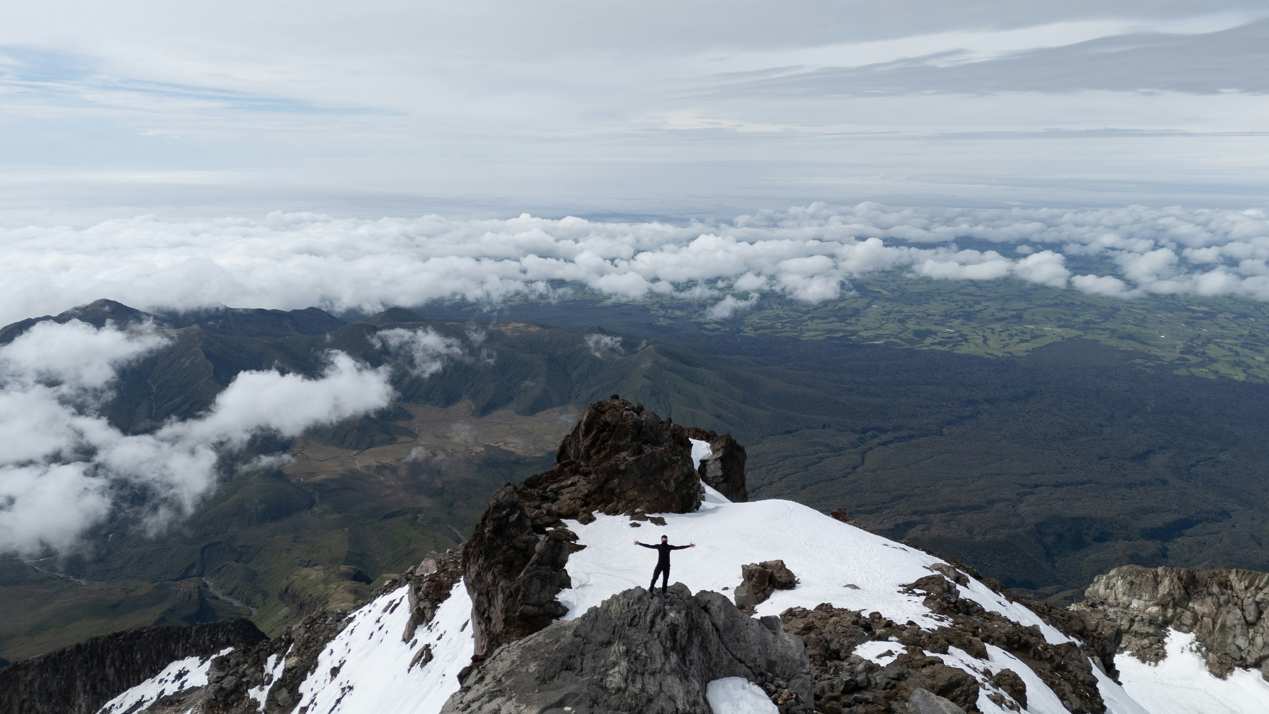 Un hombre de pie en la cima de una montaña cubierta de nieve