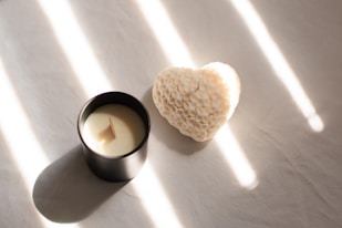 A candle with a heart shaped candle holder next to it