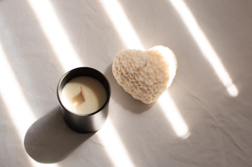 A candle with a heart shaped candle holder next to it