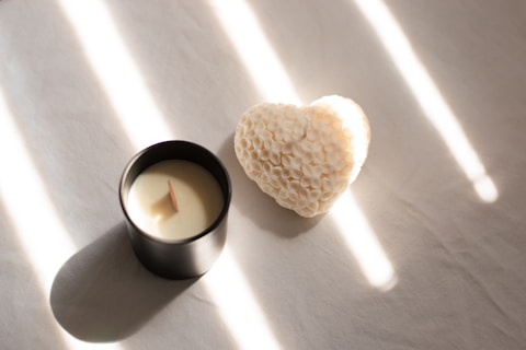 A candle with a heart shaped candle holder next to it