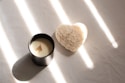 A candle with a heart shaped candle holder next to it