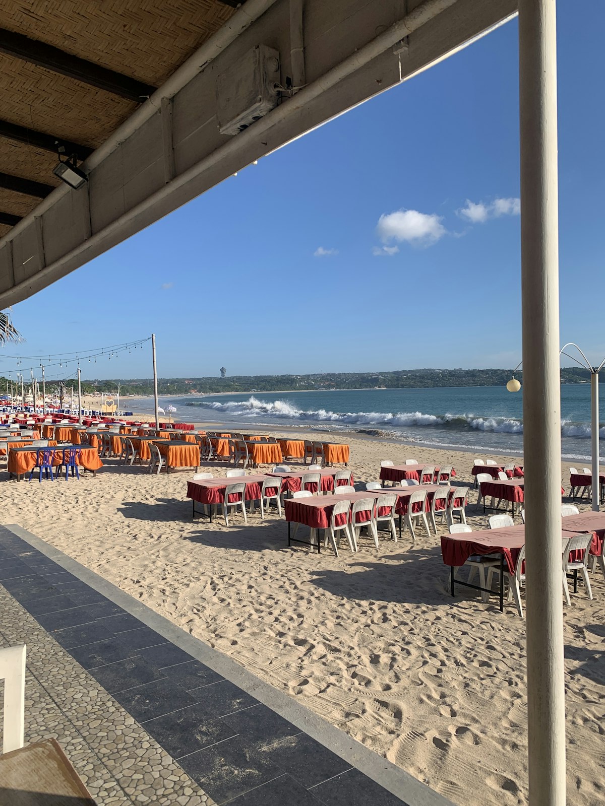 Beach tables and chairs set out for a Jimbaran seafood dinner at sunset