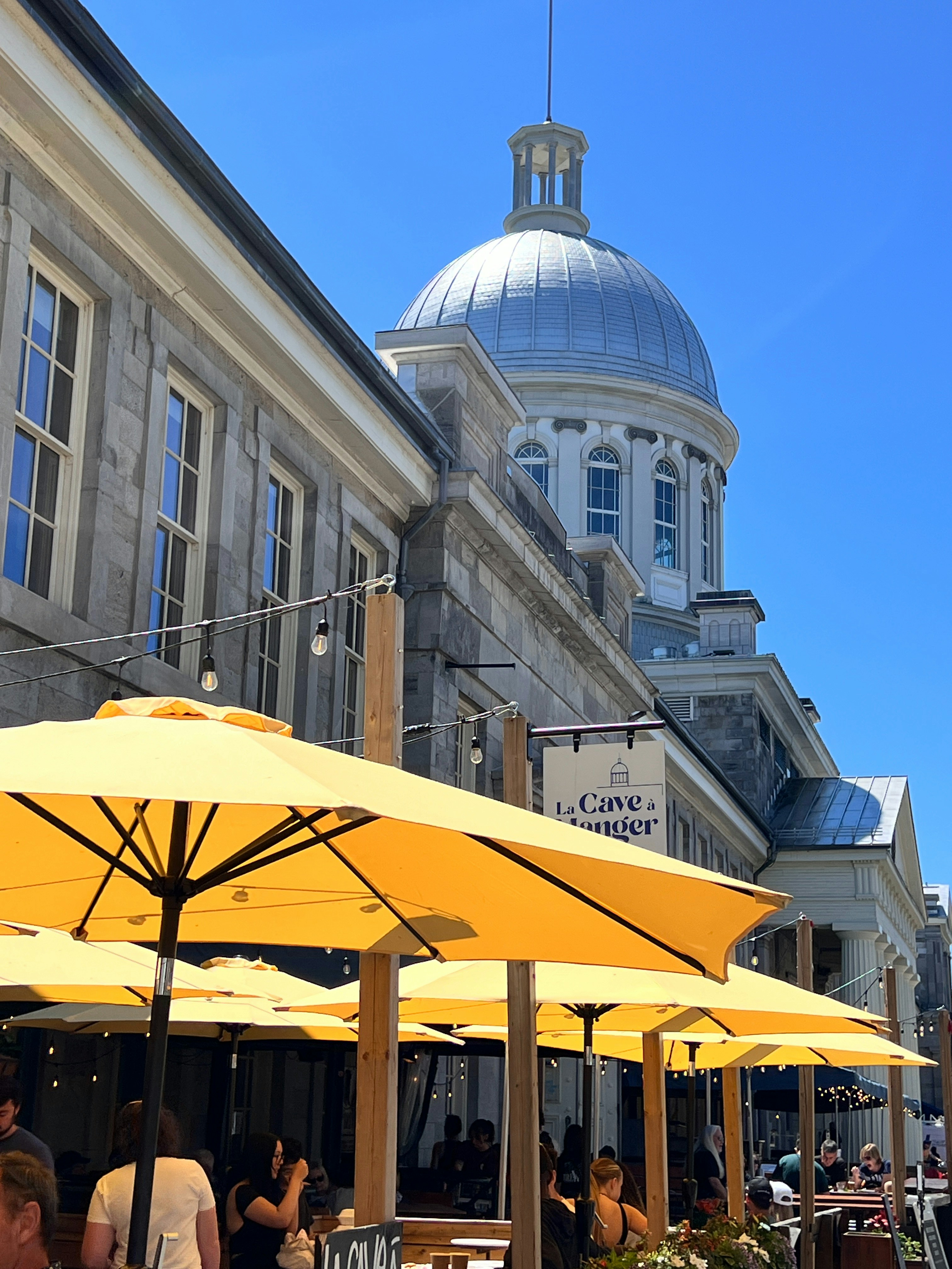 A group of people sitting at tables under yellow umbrellas
