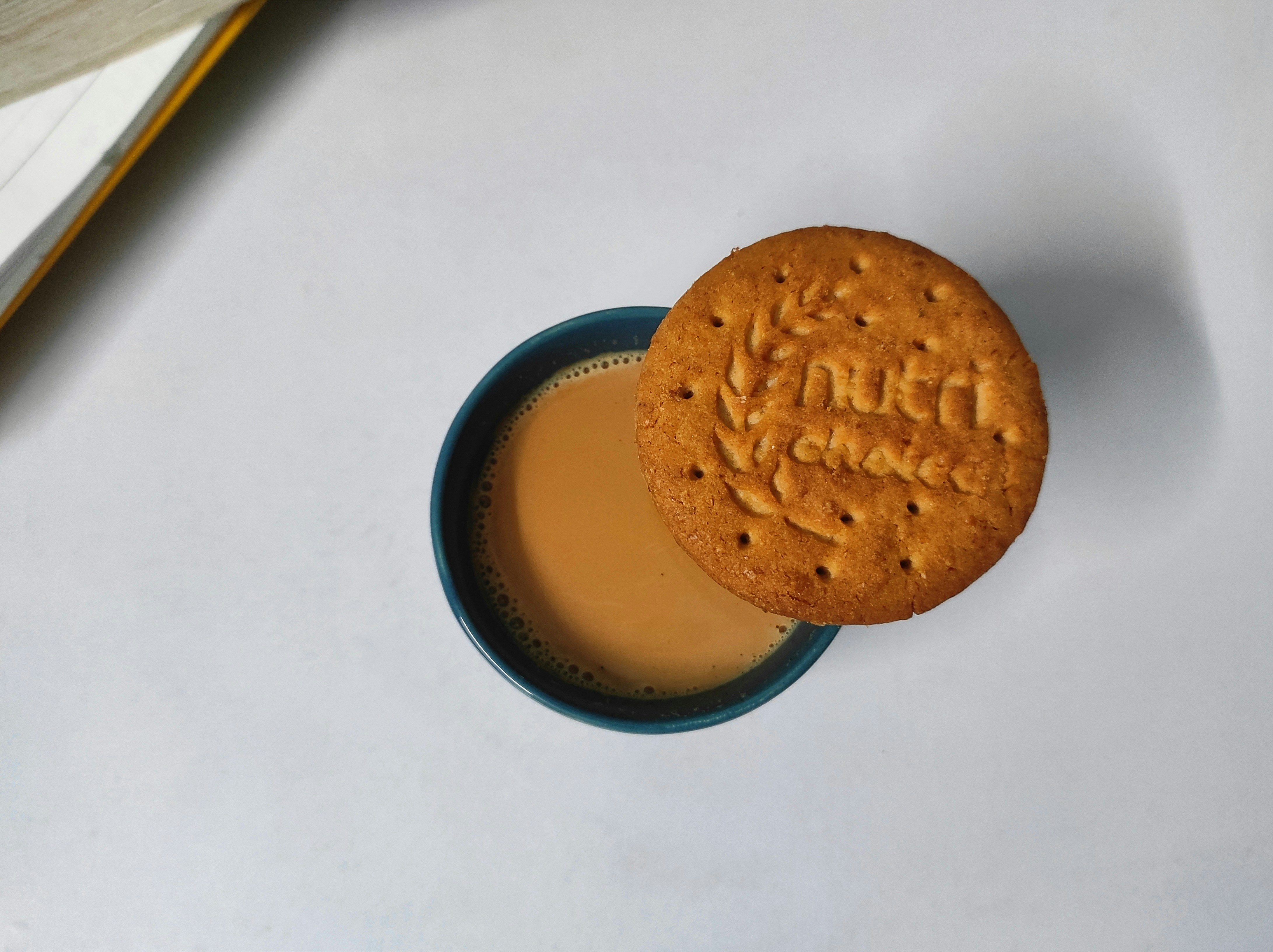 A cookie sitting on top of a table next to a book