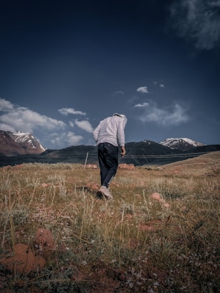 A person walking in a field with mountains in the background
